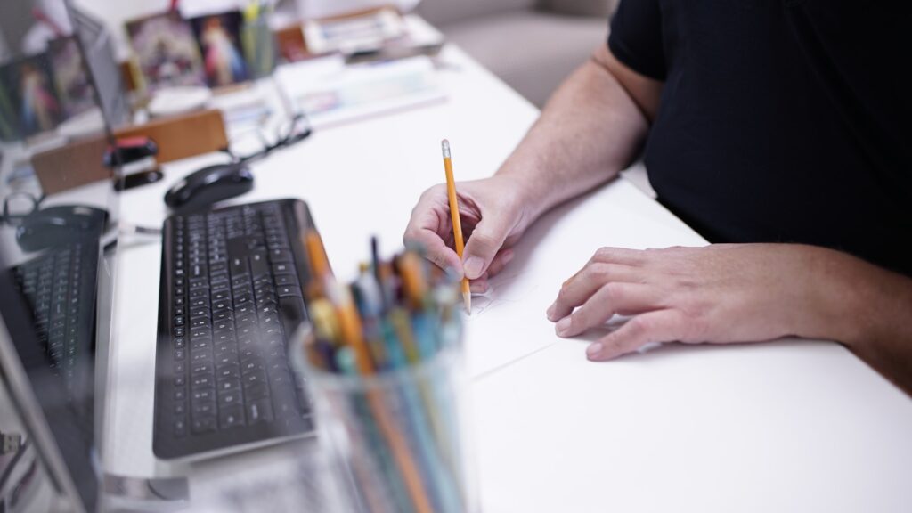 a person sitting at a desk writing on a piece of paper